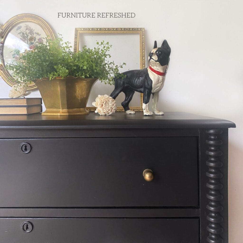 Close up of the front corner of the black painted dresser, highlighting the antique bronze drawer pulls.