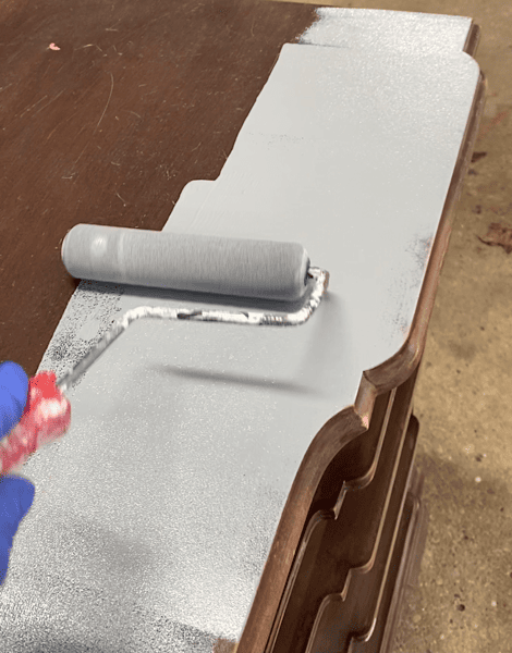 photo of rolling a gray primer onto the top of a piece of furniture