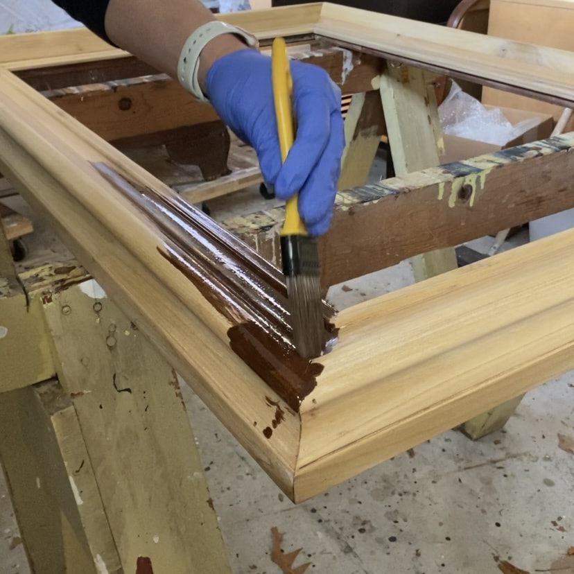 Applying wood stain to a stripped and sanded mirror.