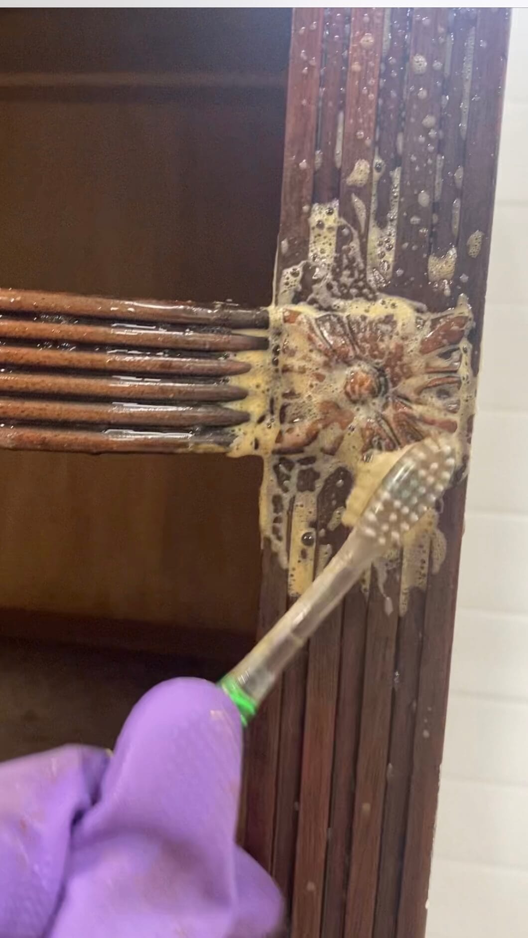 Cleaning a piece of furniture with a toothbrush.