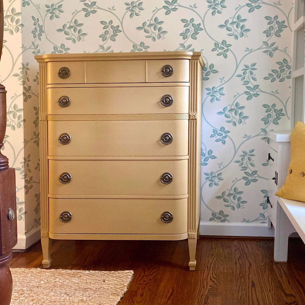 Photo of yellow painted dresser in a bedroom with blue accents.