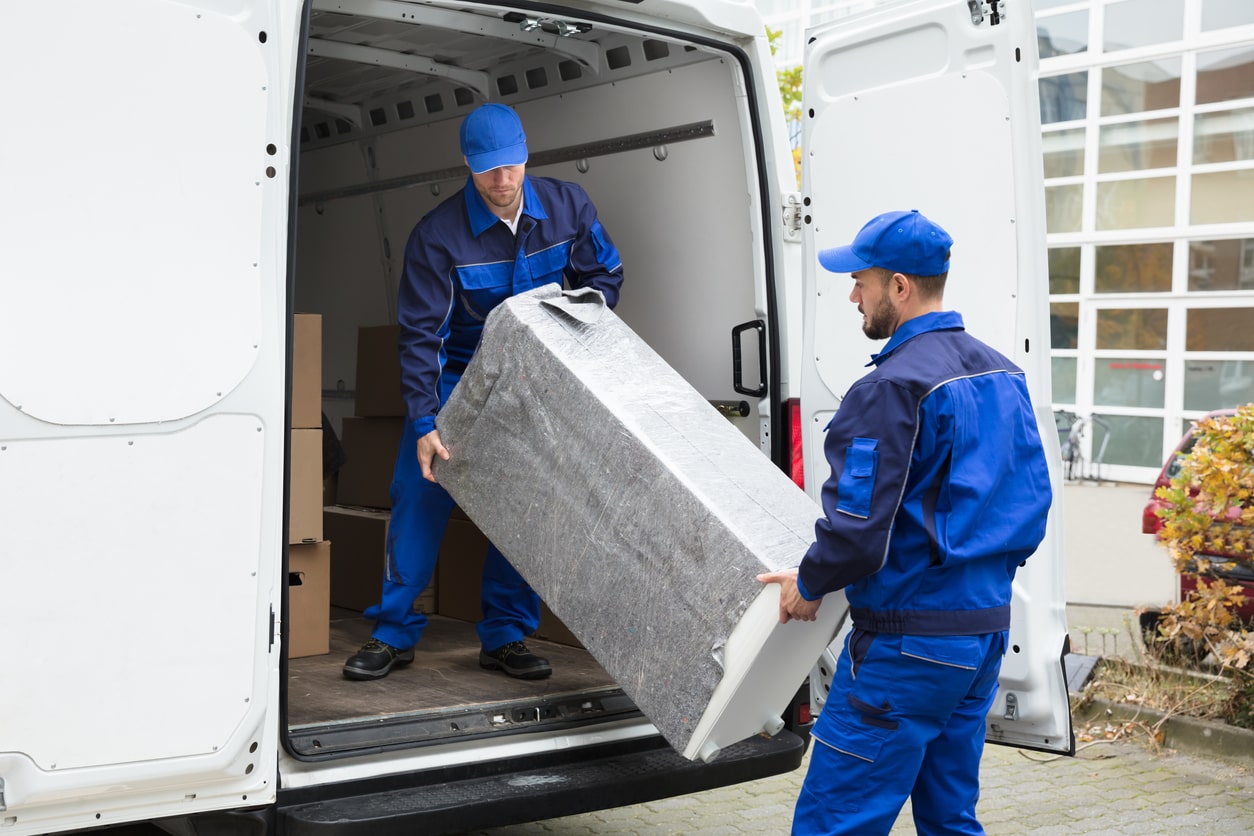 Two men loading a piece of furniture into a truck.