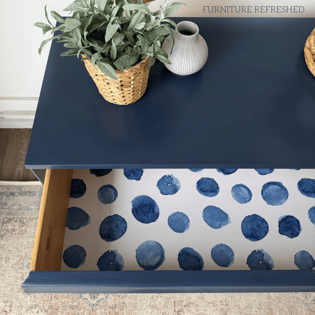 Close up photo of a dresser drawer with navy polka dot drawer liner.
