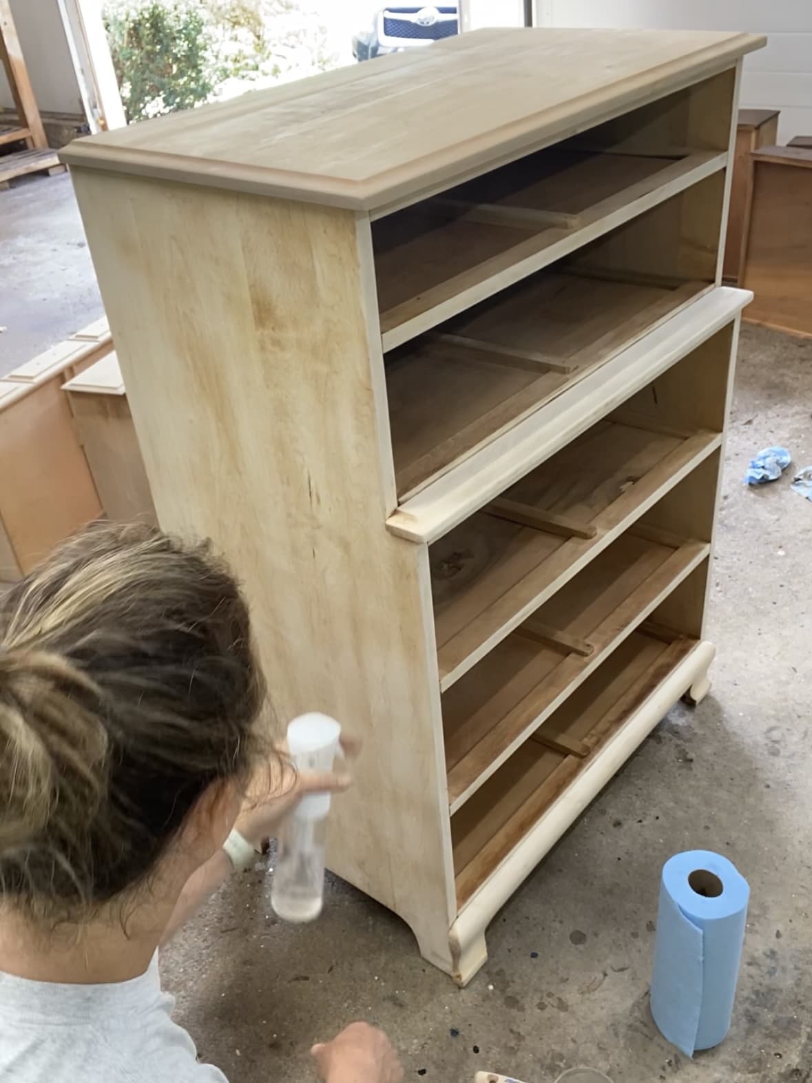 Using a misting bottle to wet the surface of a dresser that has had all of it's finish removed.