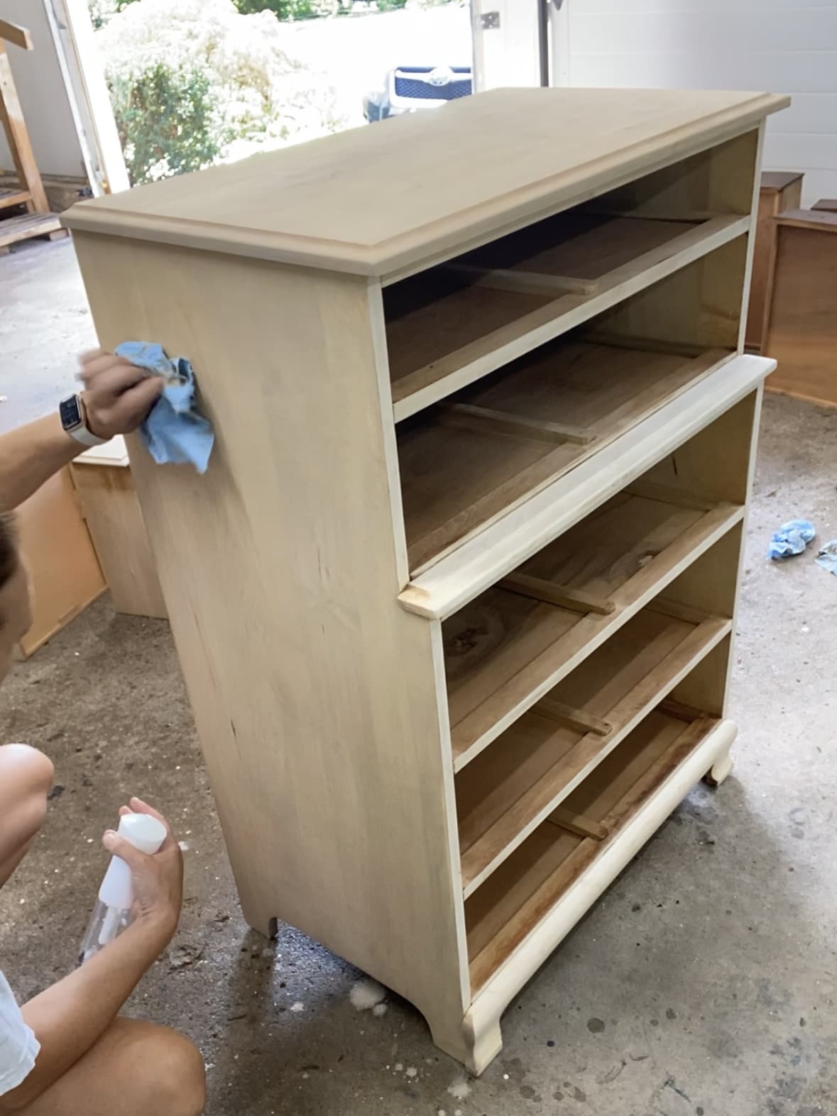 Using a blue shop towel to wipe the excess wash off of the side of the dresser.