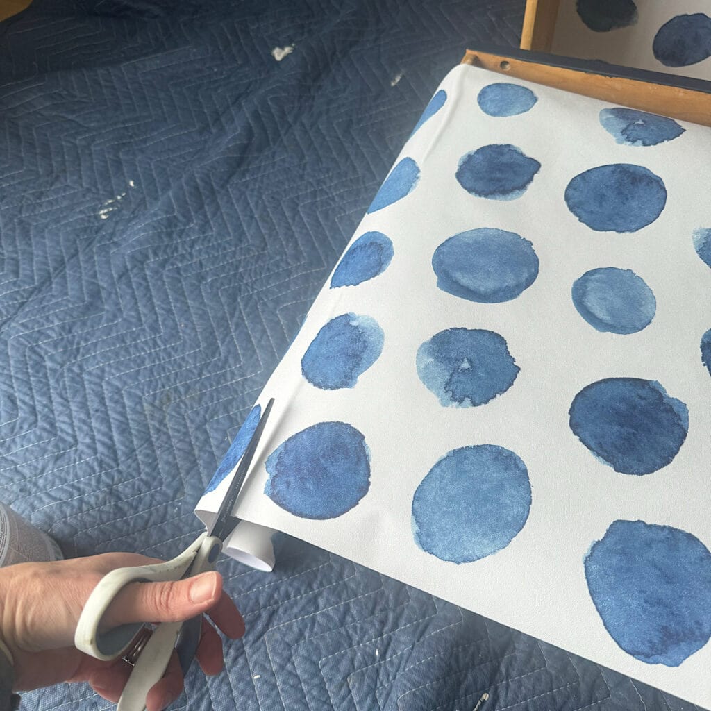 Cutting a piece of wallpaper to add as a drawer liner.