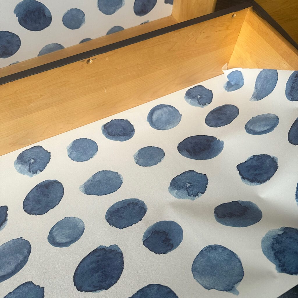 Positioning a piece of peel and stick wallpaper when lining a drawer.