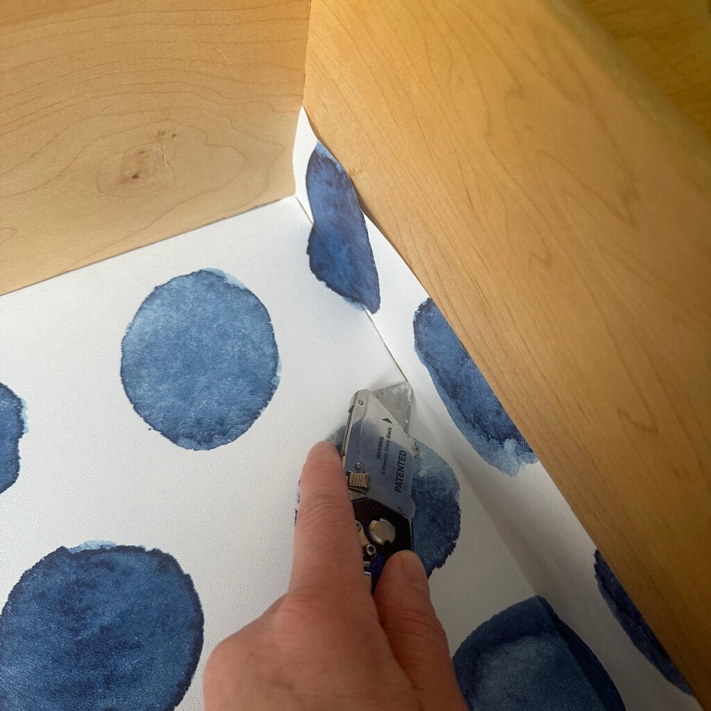 Cutting excess peel and stick wallpaper when lining a drawer.