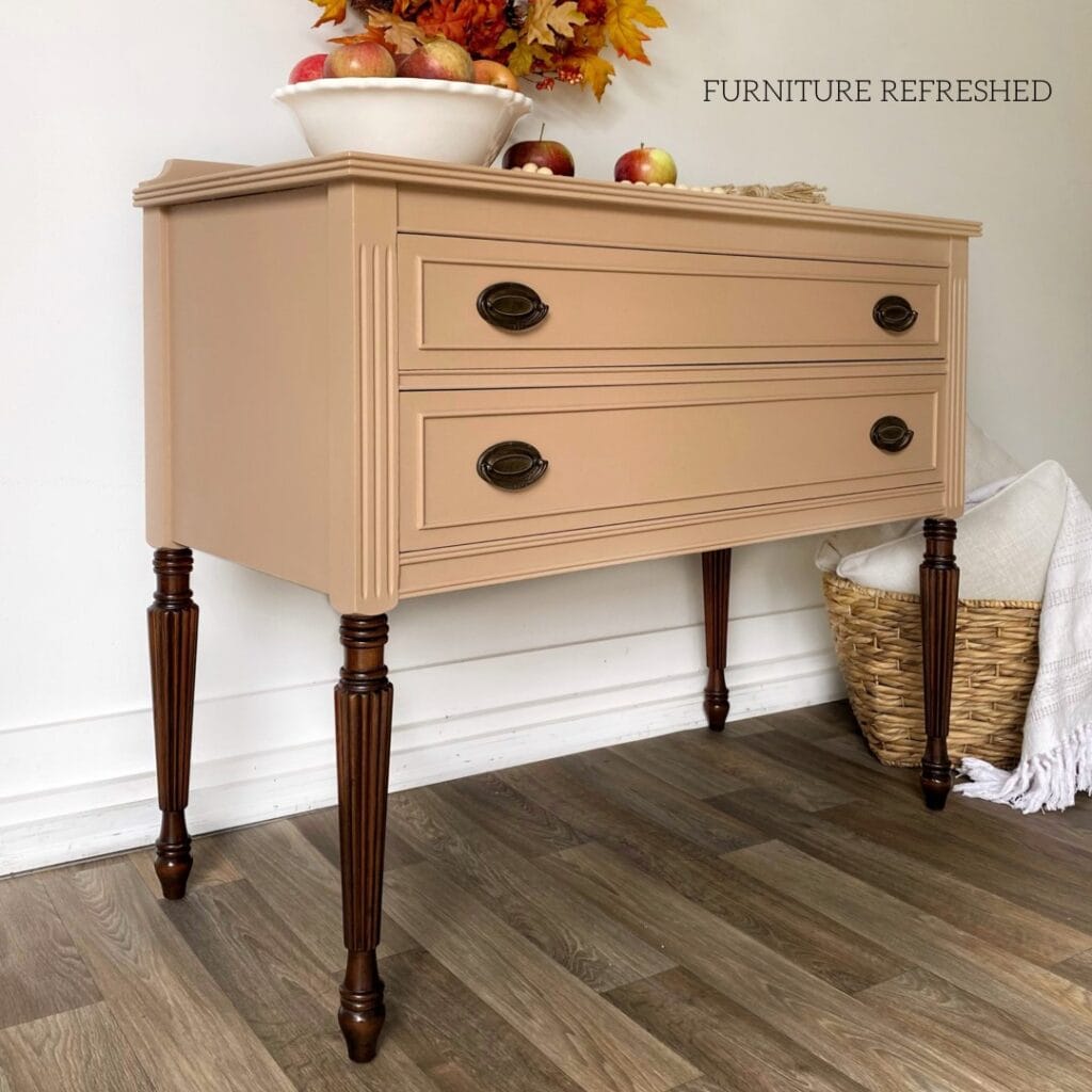 Small sideboard painted in a warm coffee colored neutral with stained wood legs.