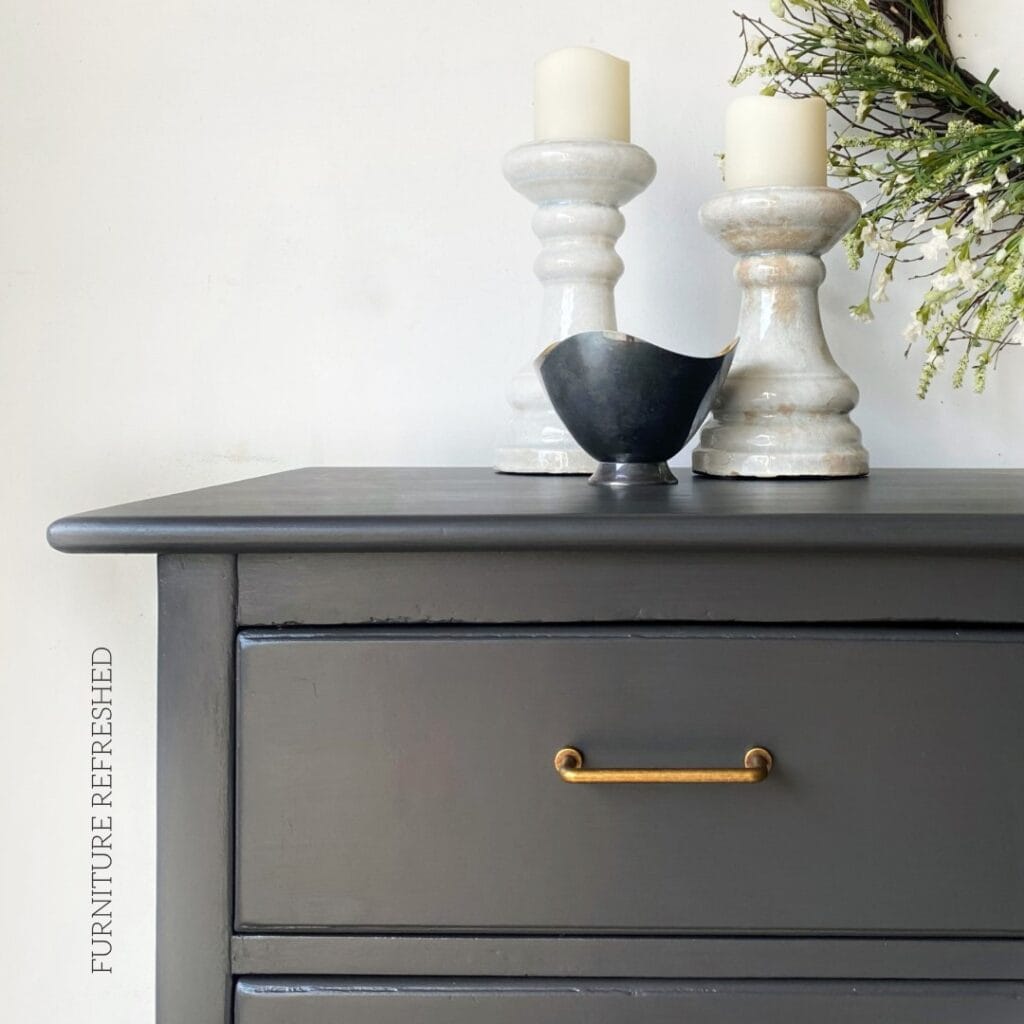 Close of up drawer hardware on a buffet. Hardware is aged brass, table is charcoal gray.
