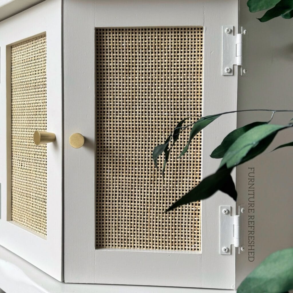 Close up of cane webbing in a small cabinet door. Wood part of the cabinet is painted white.