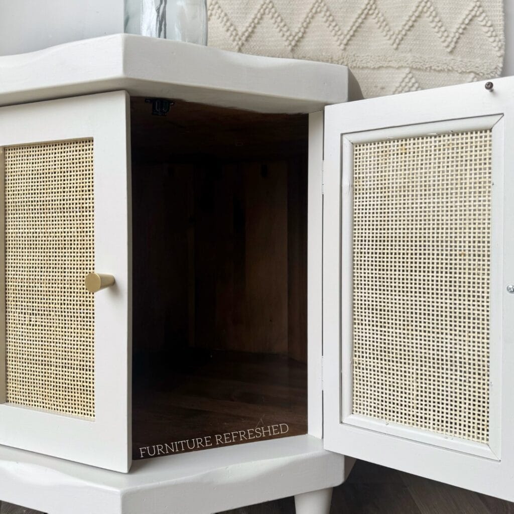 Close up of cane webbing in a small cabinet door, from the inside. Wood part of the cabinet is painted white.