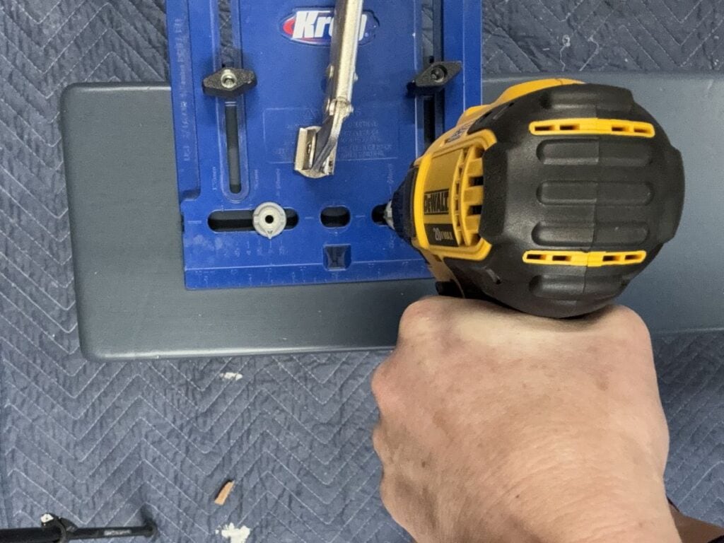 Drilling new hardware holes on a dresser drawer using a Kreg hardware jig.