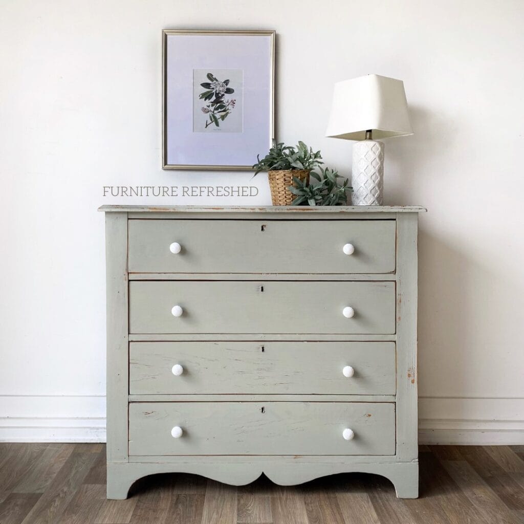 Pine dresser painted in a light blue/green milk paint with white ceramic knobs.