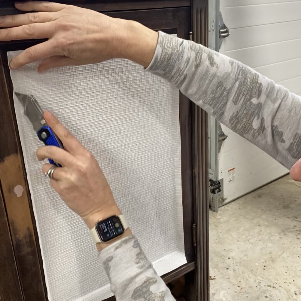 Cutting the excess paper from installed paintable wallpaper.