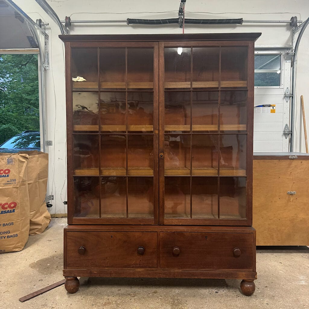 Before photo of brown wood cabinet with glass paned doors that was used in this project.