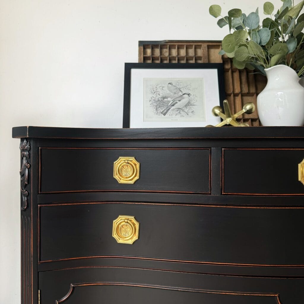Close up photo. of the painted and distressed sideboard. Front view of the top conner with the top two drawers partially visible and you can see the wood on the edges of the drawers.