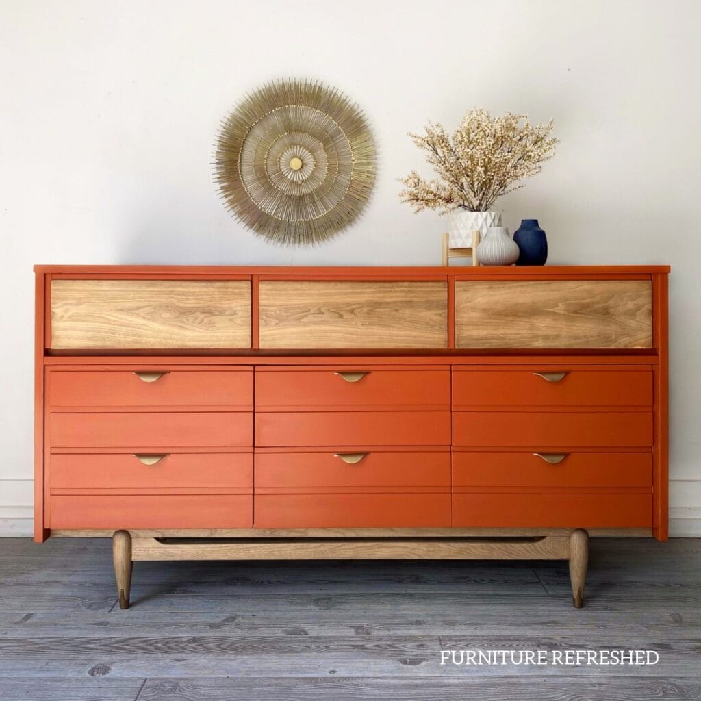 Orange 9 drawer MCM painted dresser. Top three drawers and base have a raw wood finish.