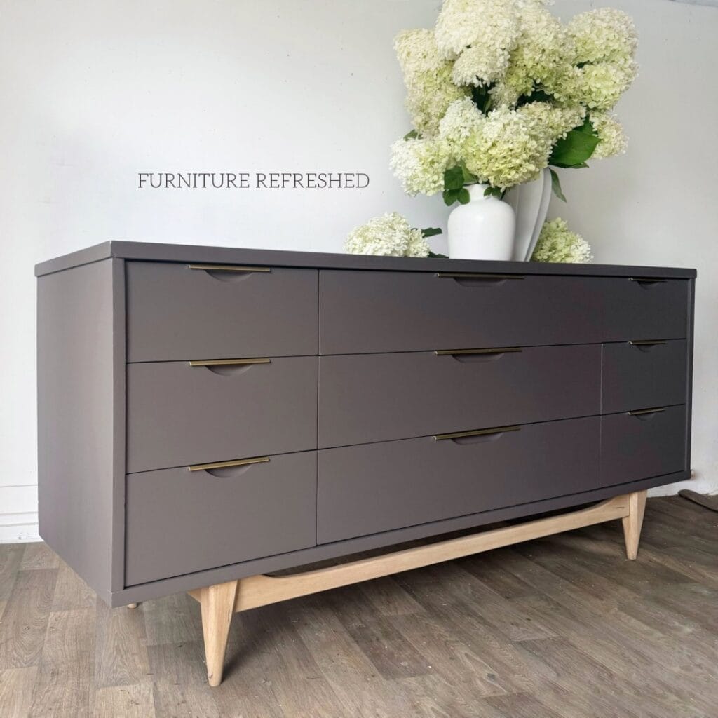 Angled view of 9 drawer mcm dresser painted in a smoky brown with a light wood base and brass pulls.