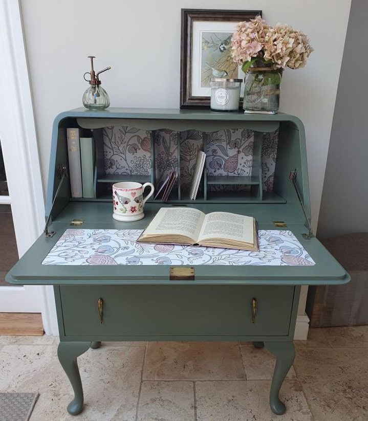 Small secretary desk painted green with a floral paper inside.