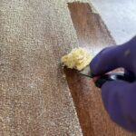 Image of a metal scraper removing the finish from the top of a table.
