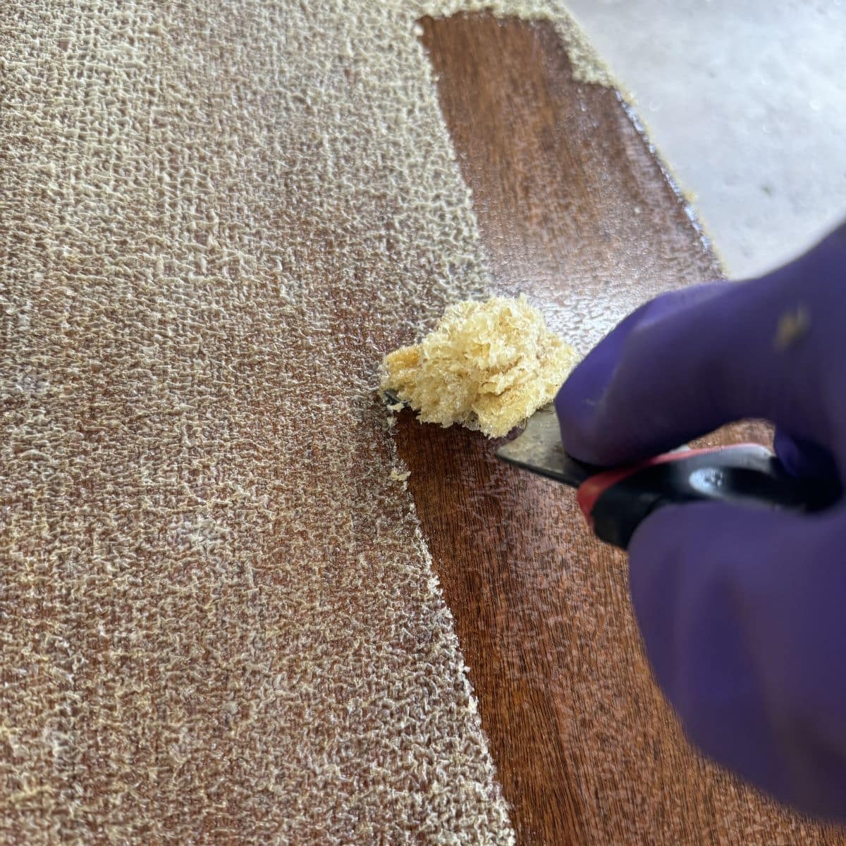 Image of a metal scraper removing the finish from the top of a table.