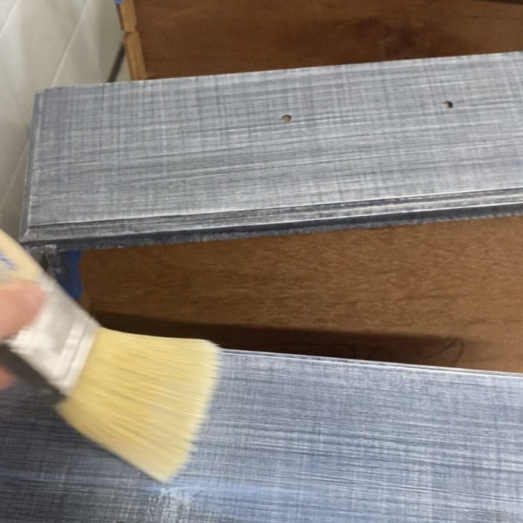 Applying topcoat with a brush to the top of a drawer.