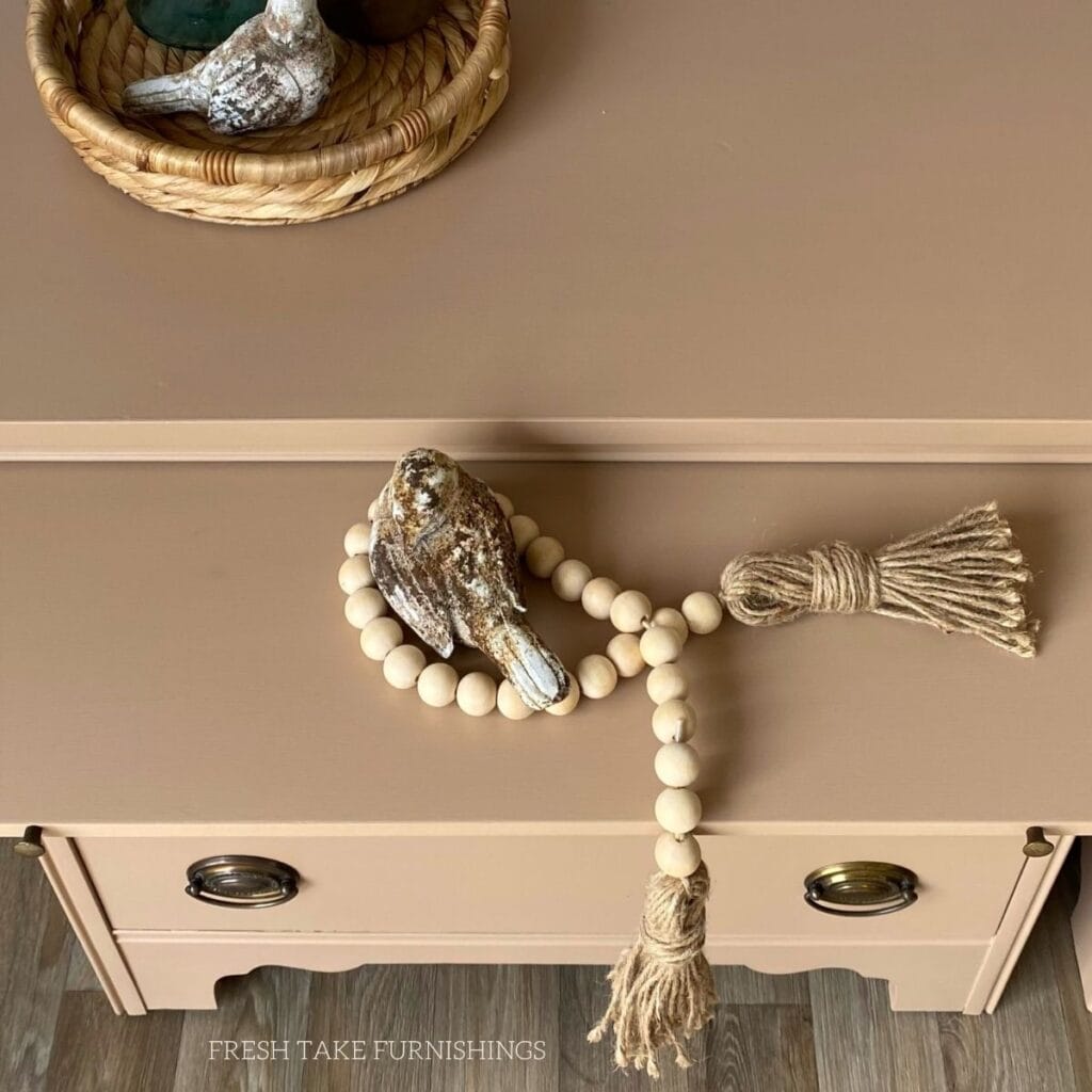 Top view of a small chest of drawers with a shelf pulled out, showcasing the tan painted furniture finish without any brushstrokes.