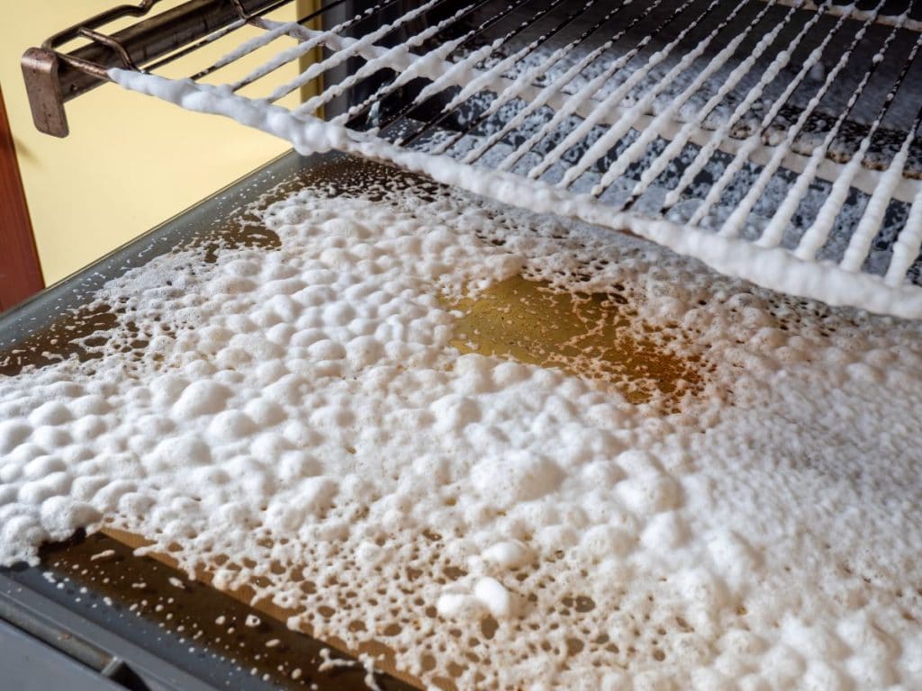 Close up of foam oven cleaner sprayed on the inside of an oven