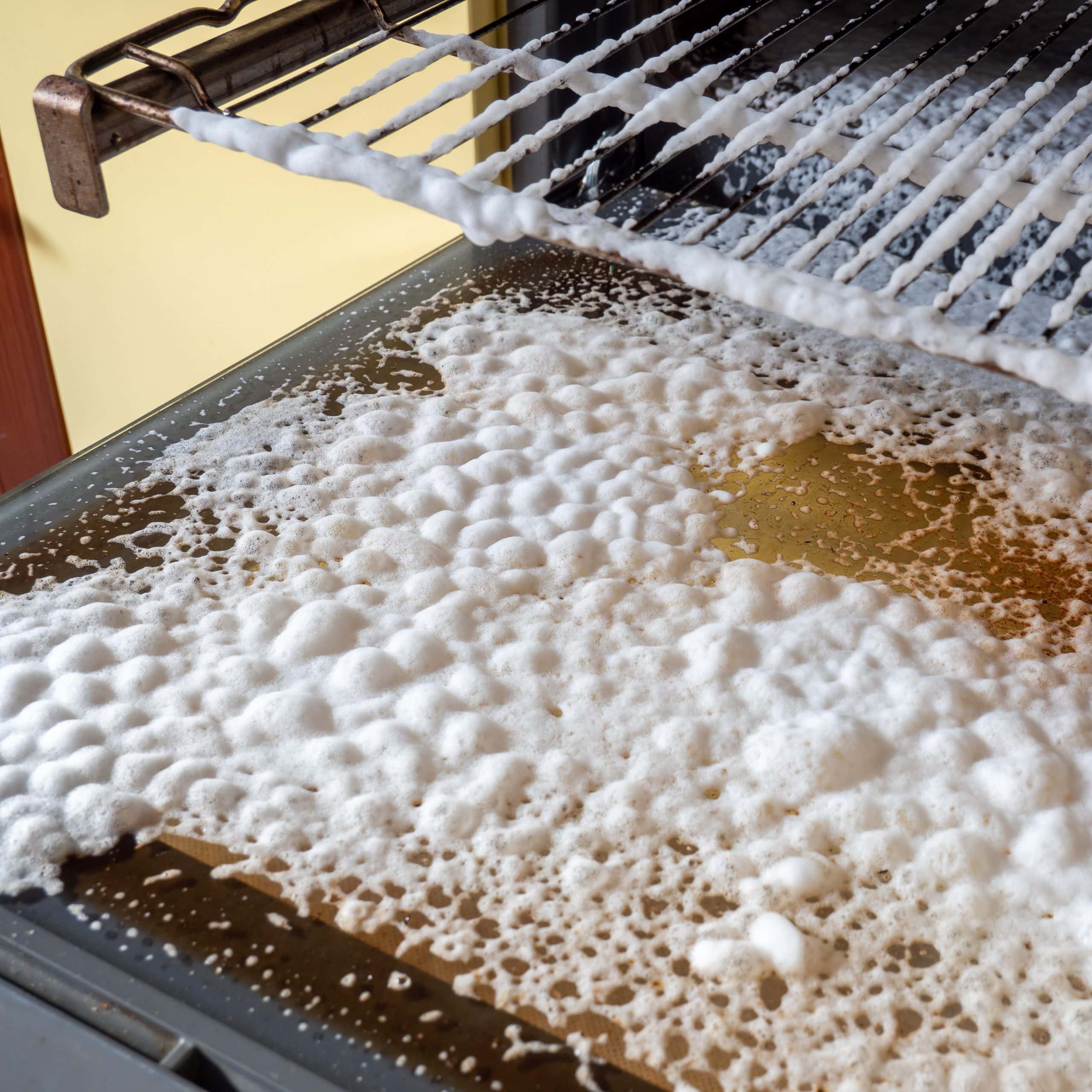 Close up of foam oven cleaner sprayed on the inside of an oven