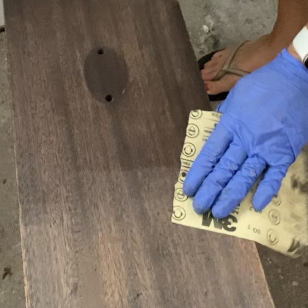 Close up of scuff sanding a furniture drawer with sandpaper.