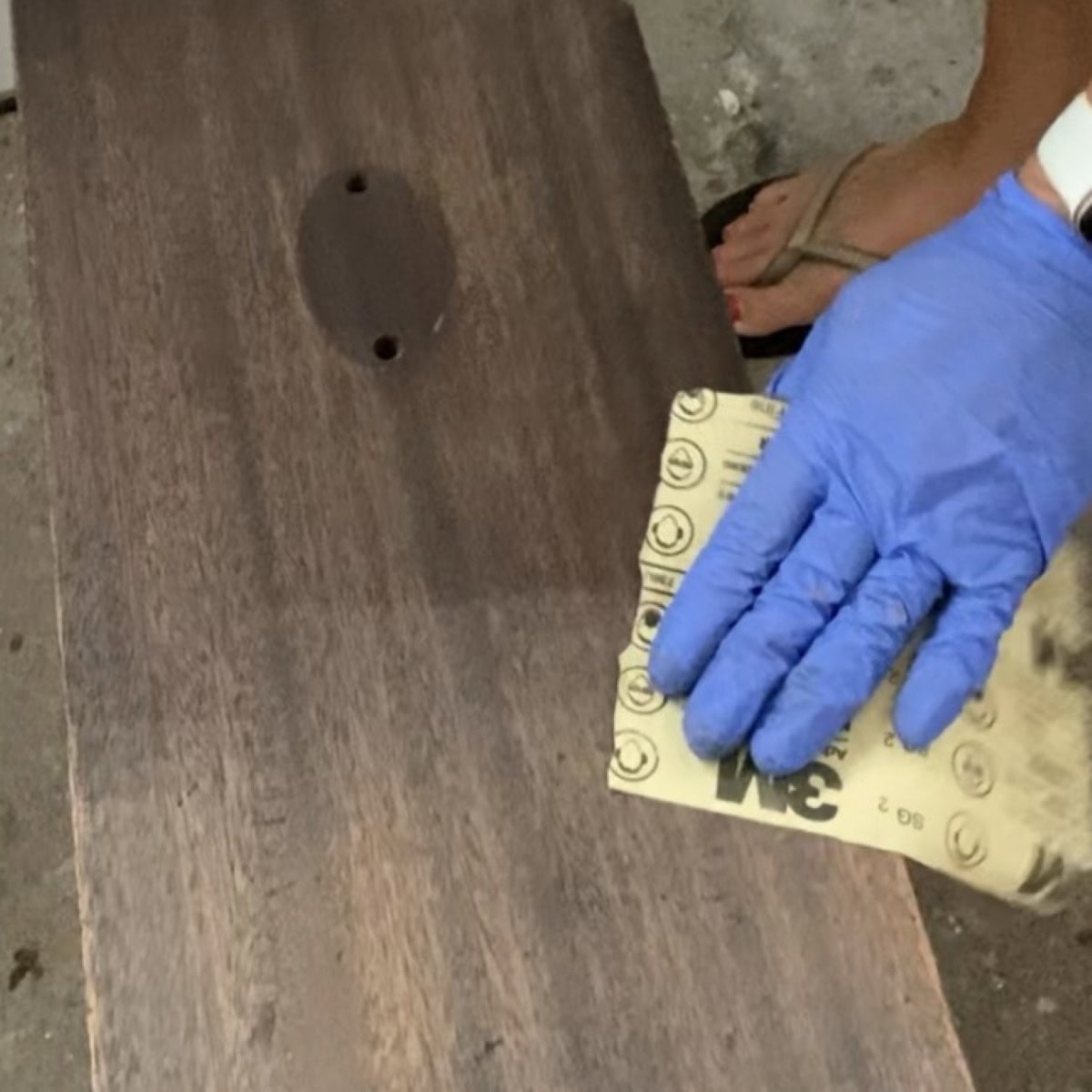 Close up of scuff sanding a furniture drawer with sandpaper.