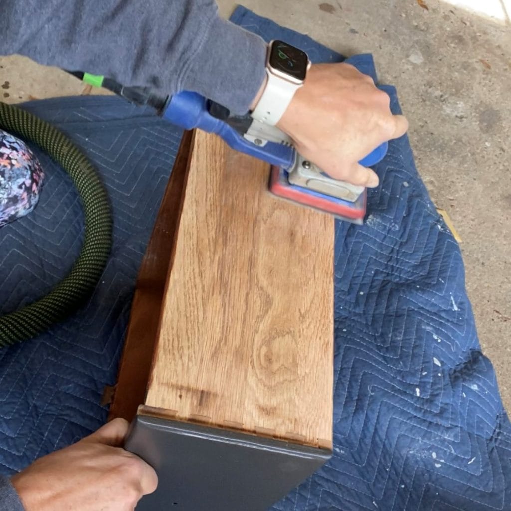 Using a surfprep sander to sand the sides of a dresser drawer/