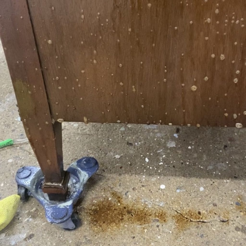 Phpto of dirty cleaning soluation dripping off of a dresser after it has been sprayed on.