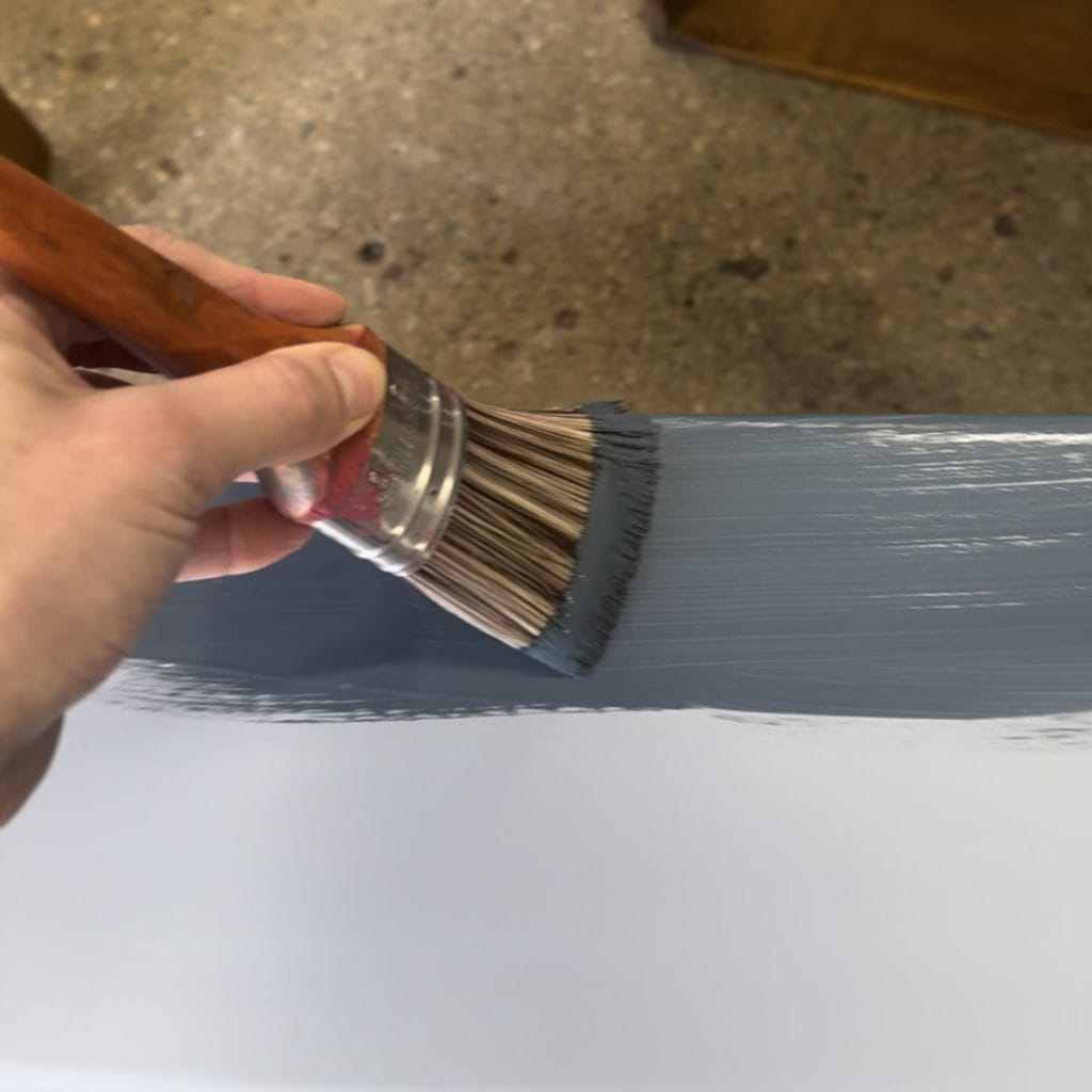 Applying navy furniture paint with a brush.