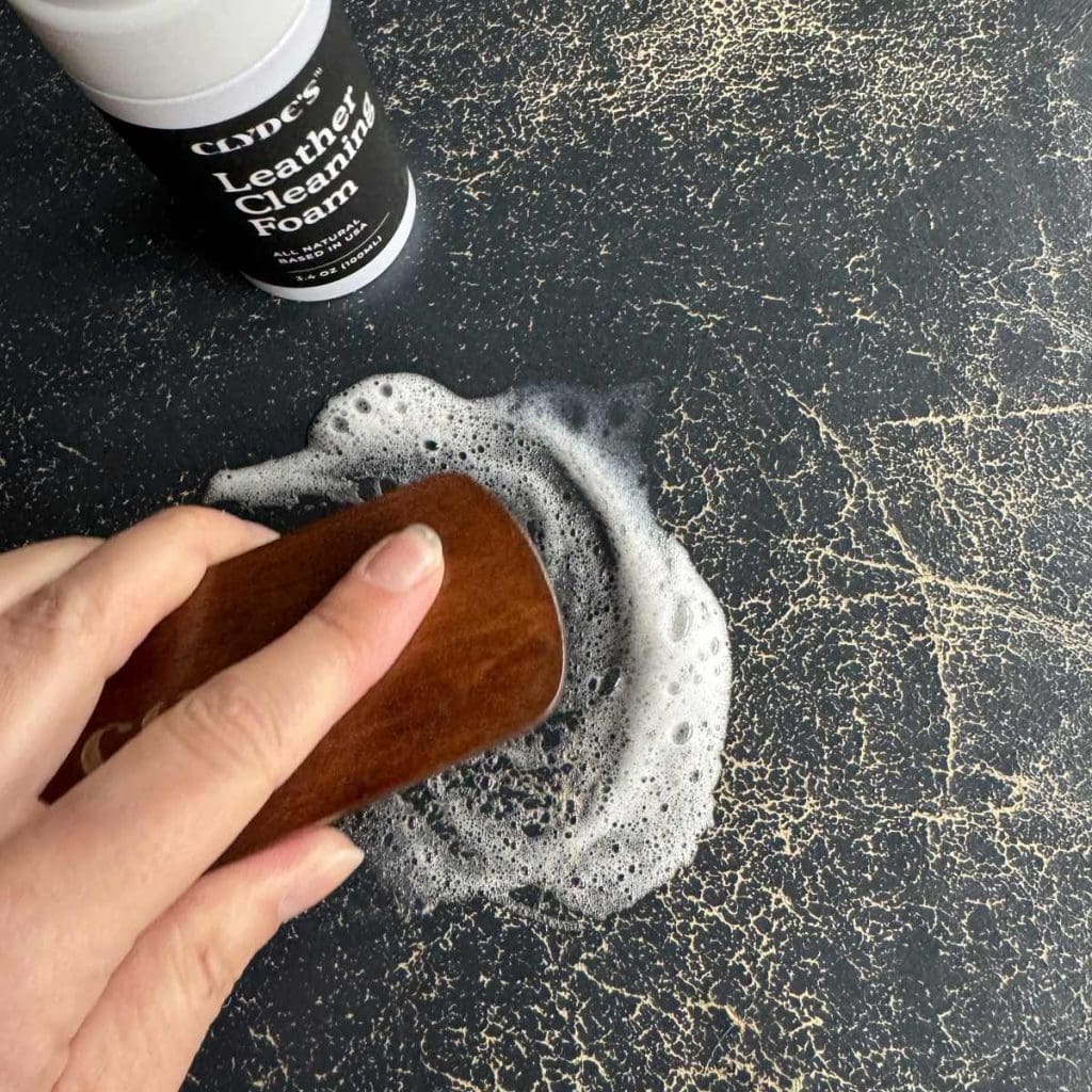 Using the brush and cleaning foam to clean the leather.