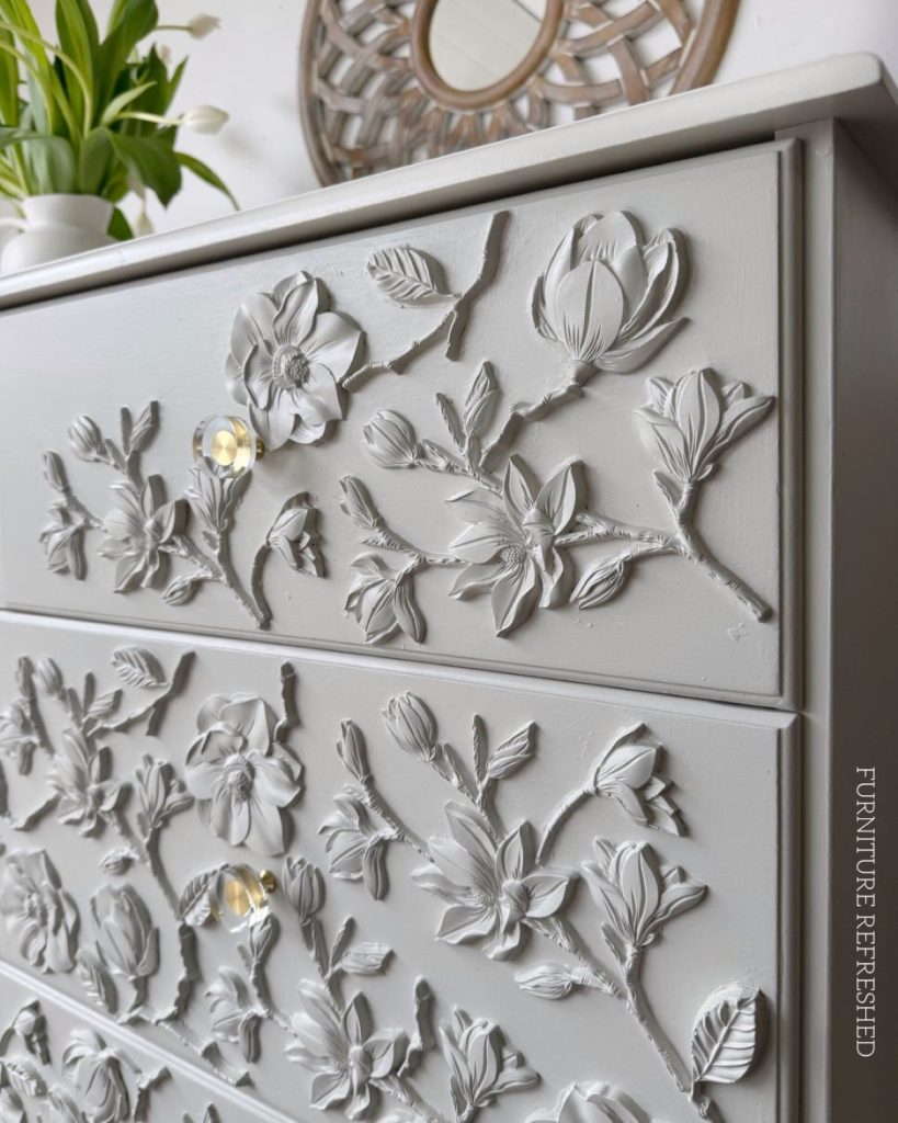 Angled, close up of painted floral appliques and hardware.