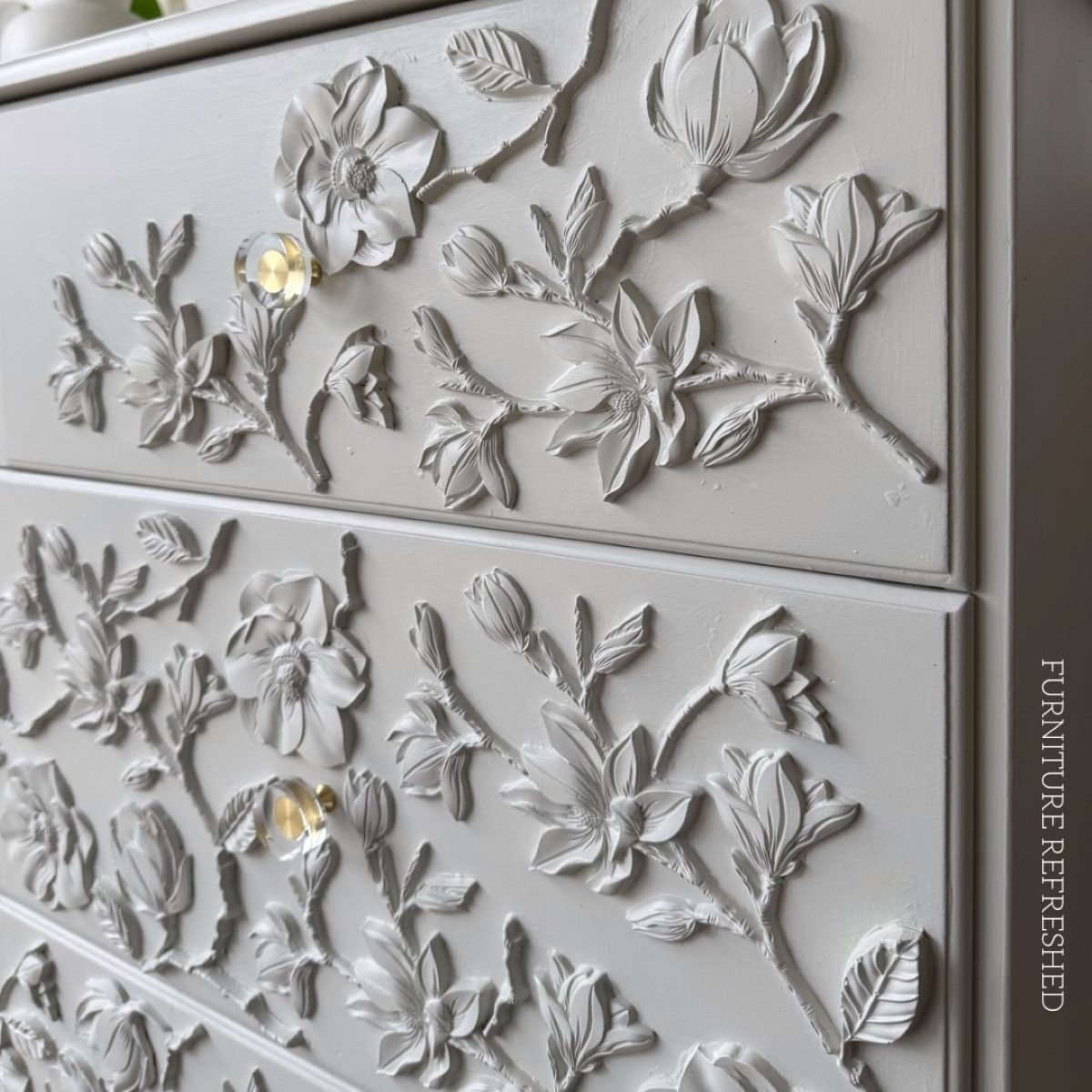 Angled, close up of painted floral appliques and hardware.