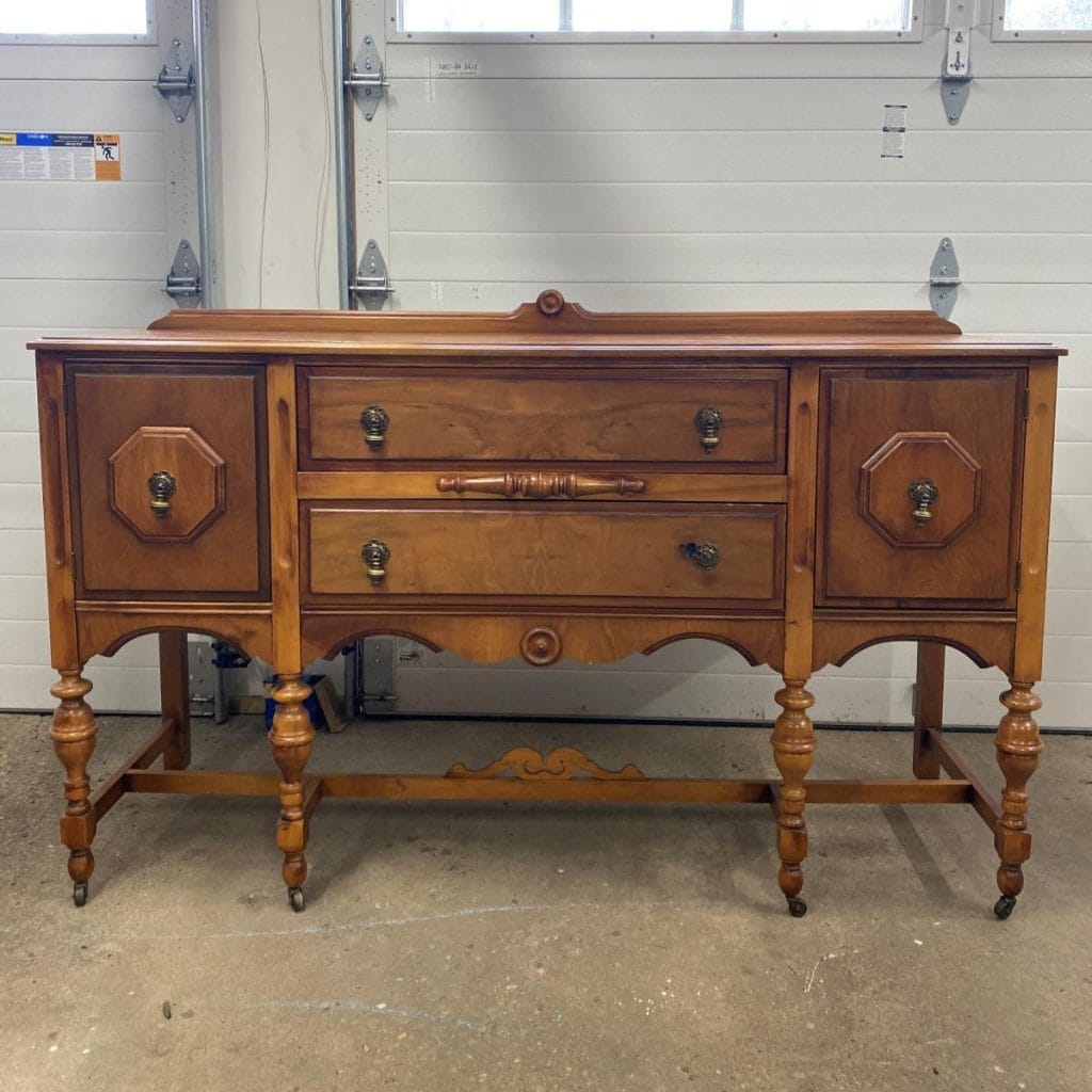 Before photo of a vintage buffet in a medium wood finish with lots of different wood details. 