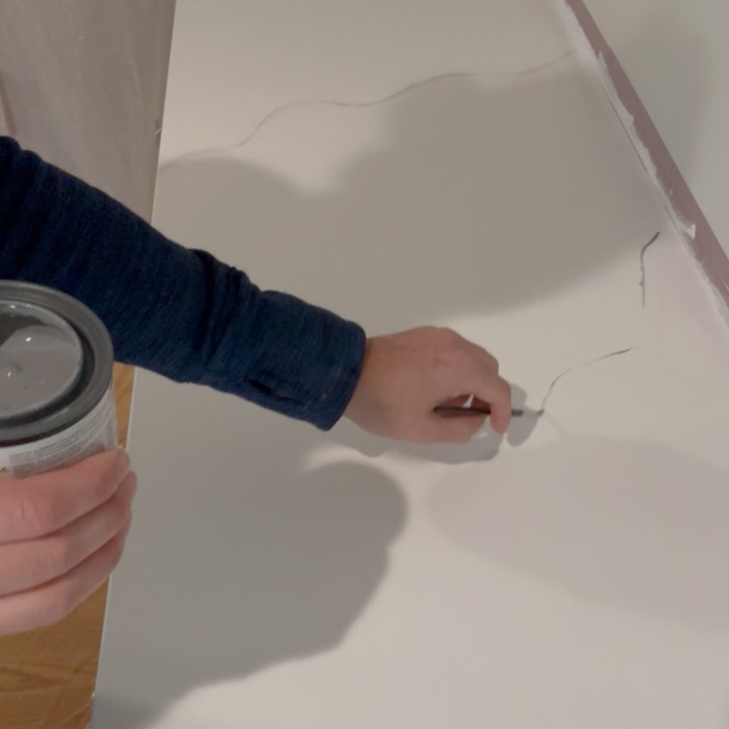 Using a small artists brush to paint on a faux marble vein.