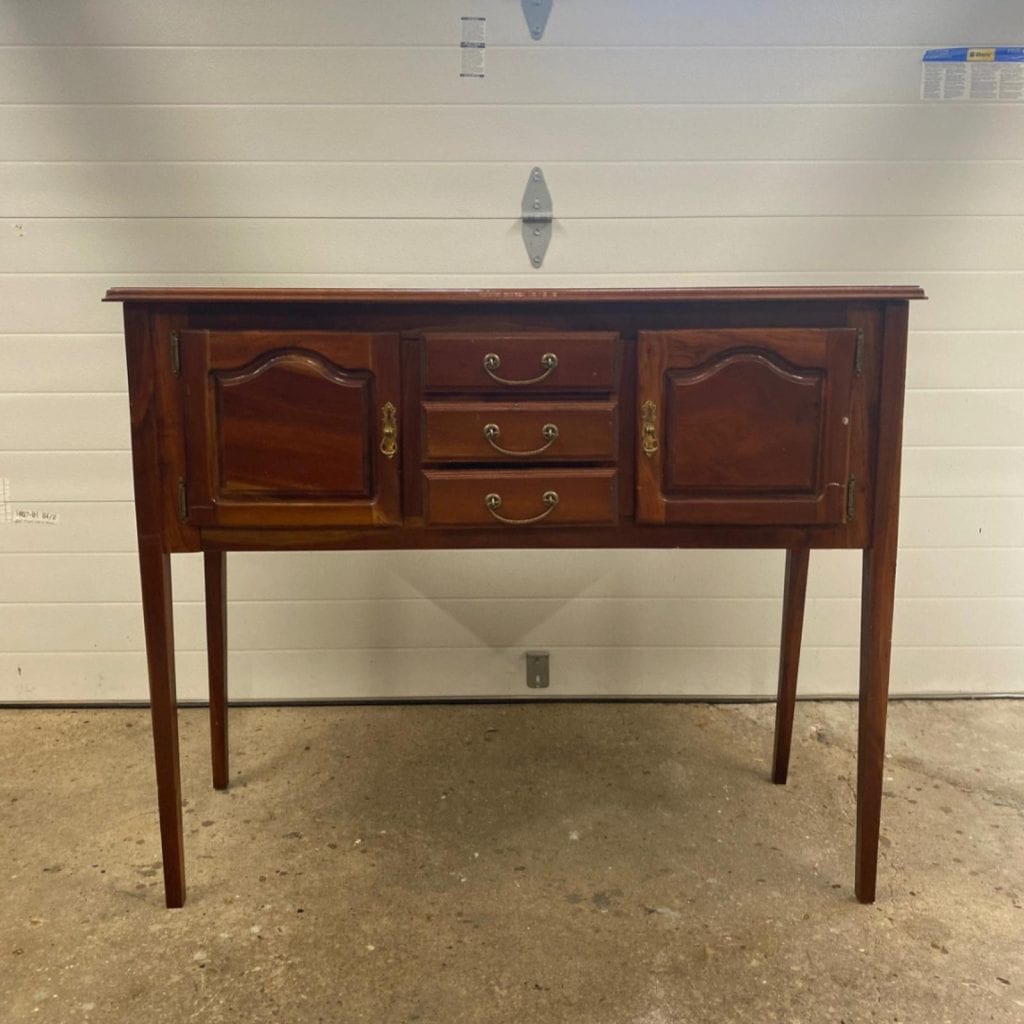 Before photo of small wooden sideboard with long legs