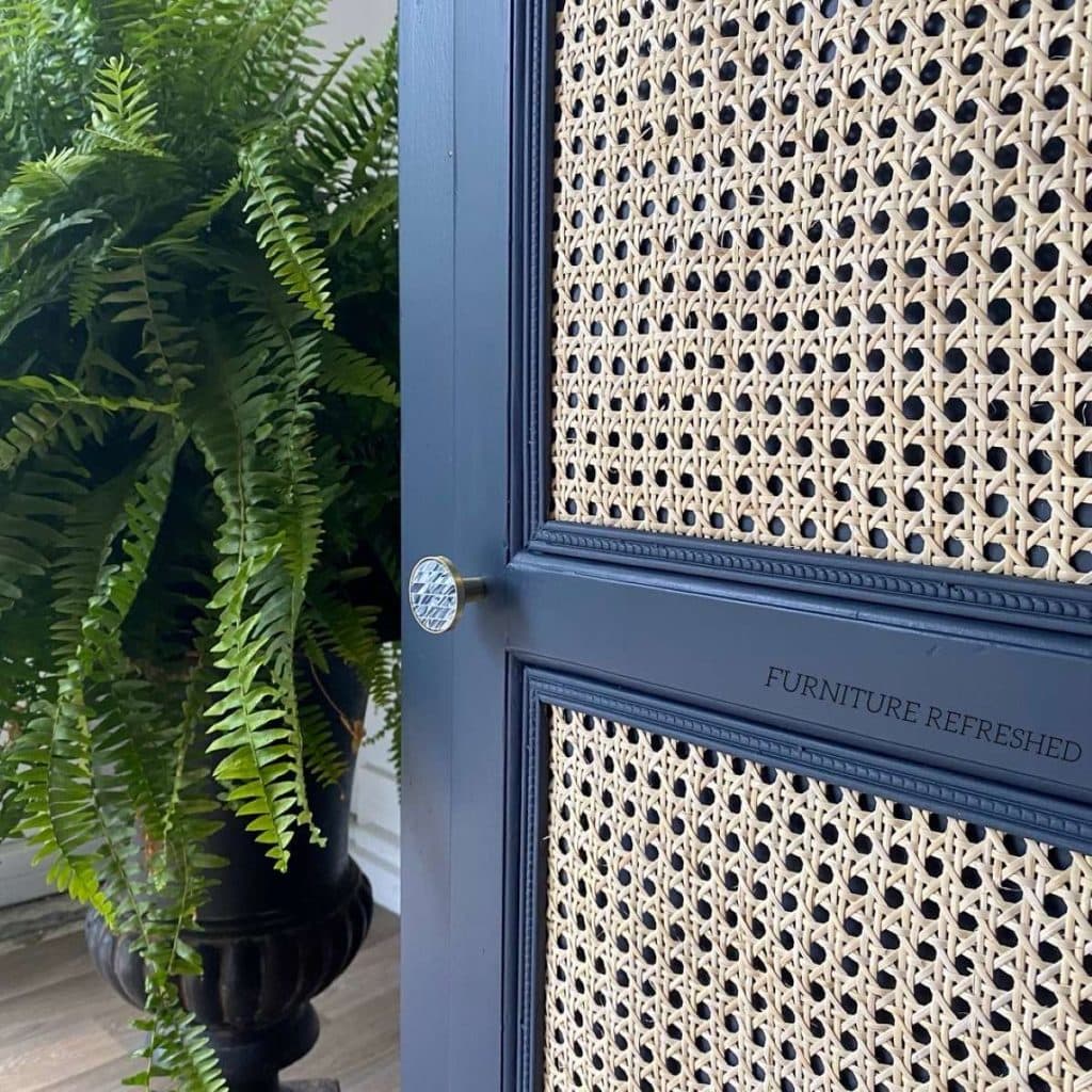 Close up of blue cabinet door with cane webbing glued on top of the panels.
