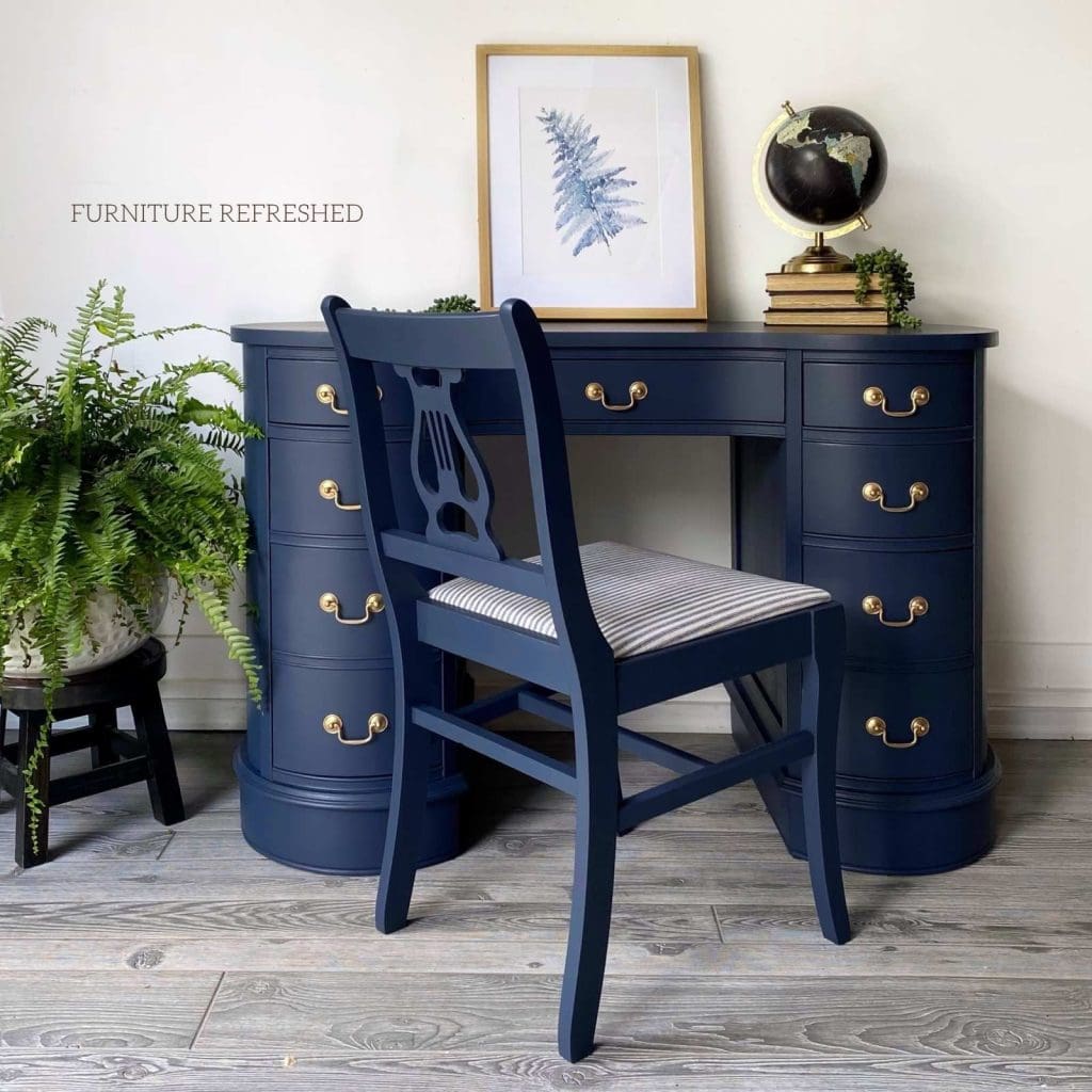 Desk painted navy blue with coordinating chair with ticking stripe upholstery on the seat.