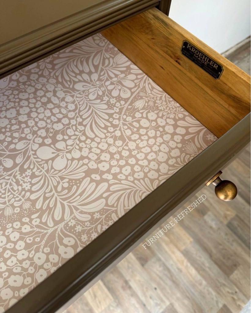 Close up of inside of drawers lined with beige floral peel and stick wallpaper.