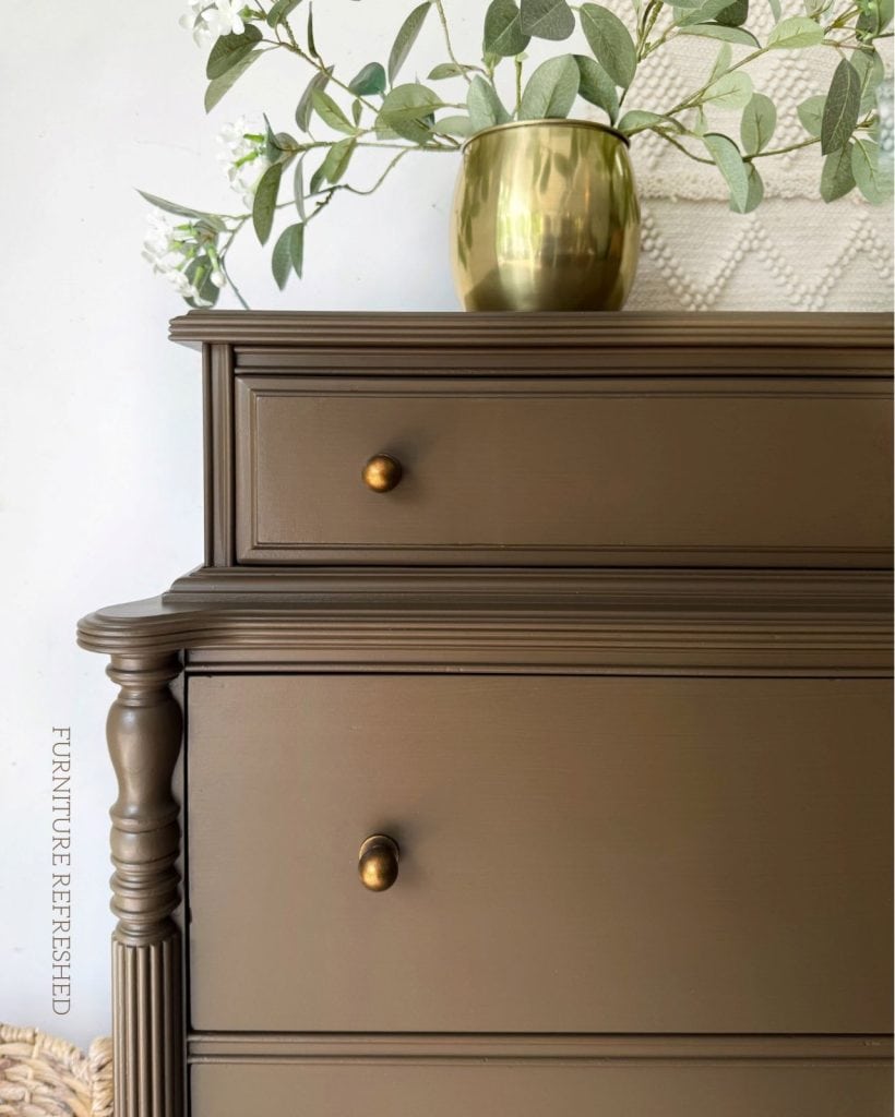 Close up of top corner of dresser with aged brass knobs.