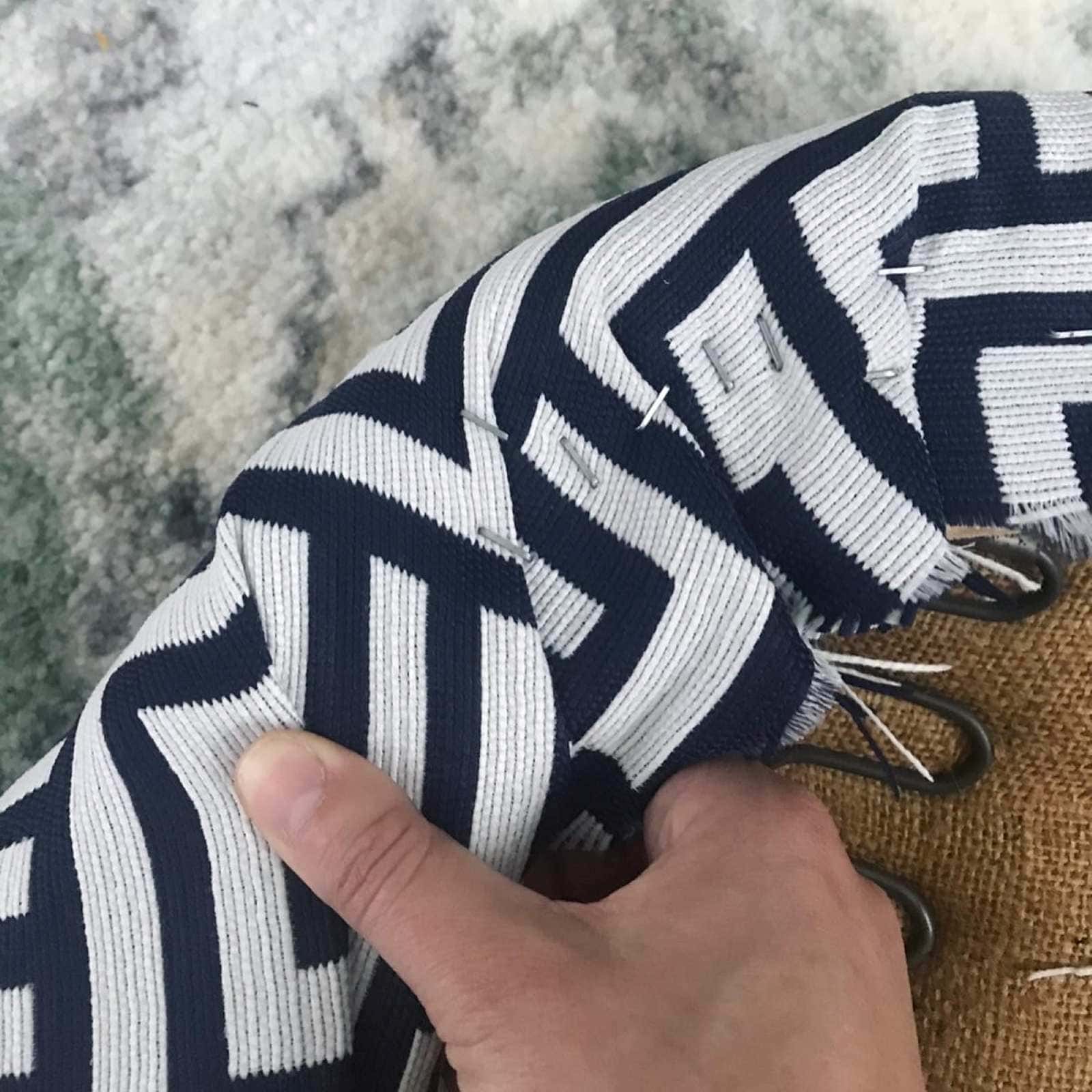 Close up of fabric being folded and stapled to the frame of the chair cushion.
