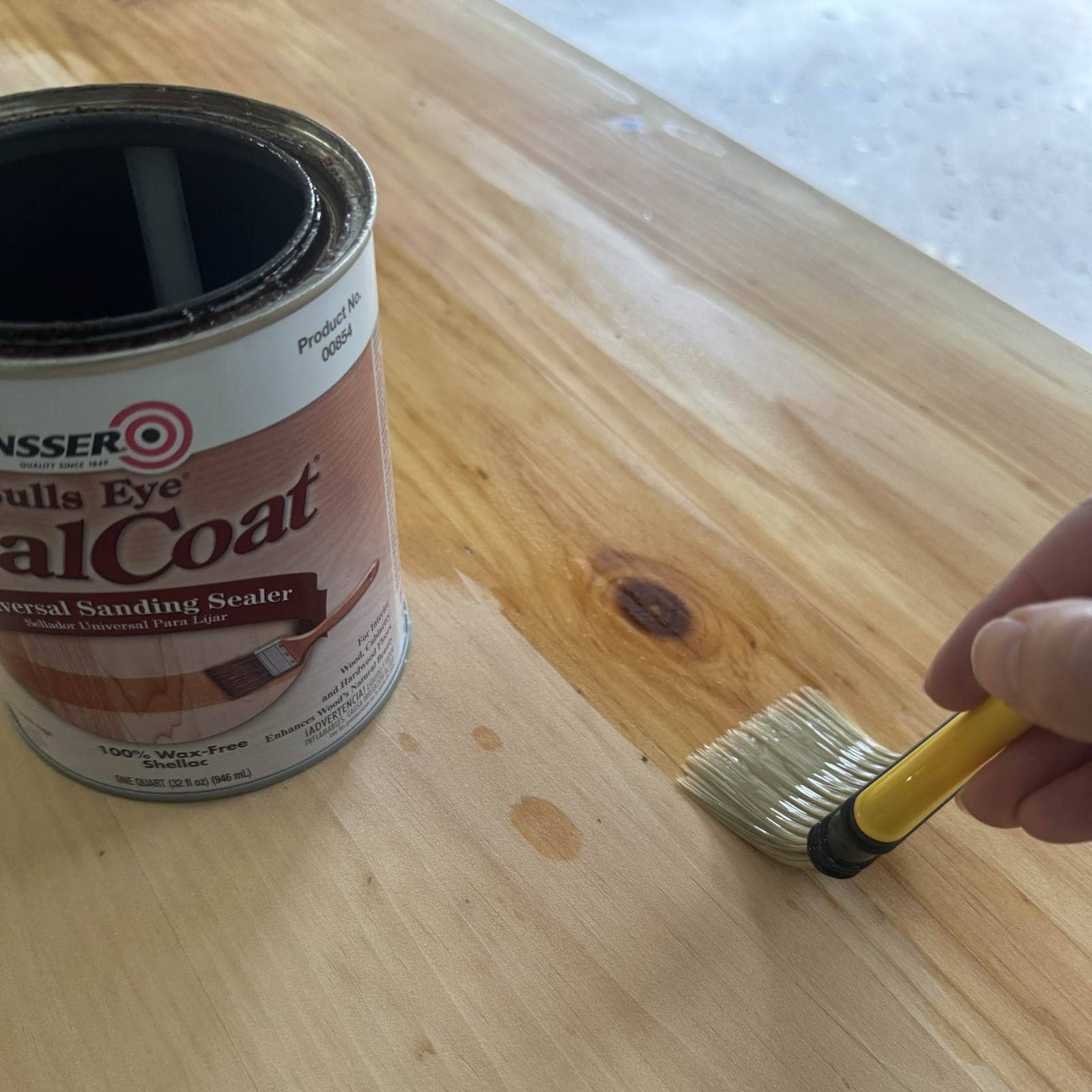 Photo of application of shellac on a raw wood surface with a chip brush.