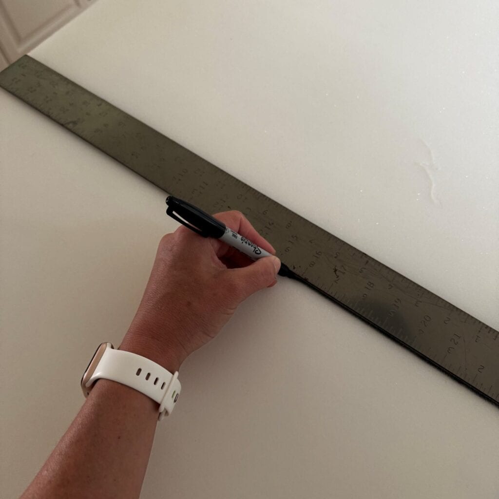 Measuring and using a marker to mark the foam for cutting.