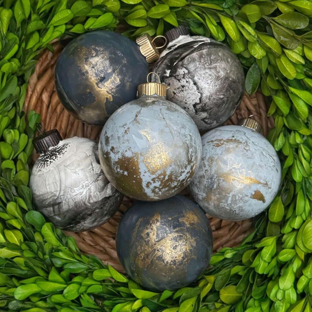 group of 6 marbled ornaments surround by boxwood greens.