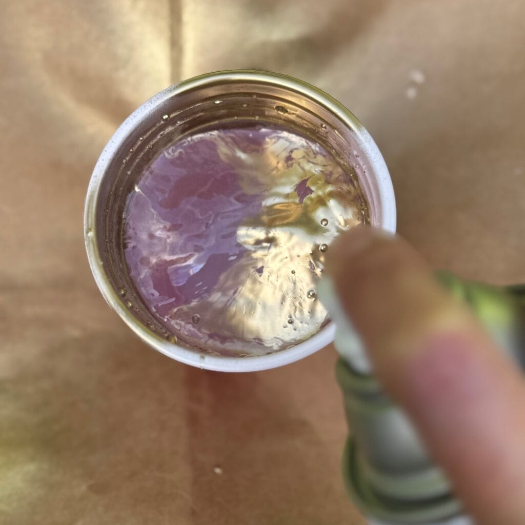 Adding spray paint to a cup of water.